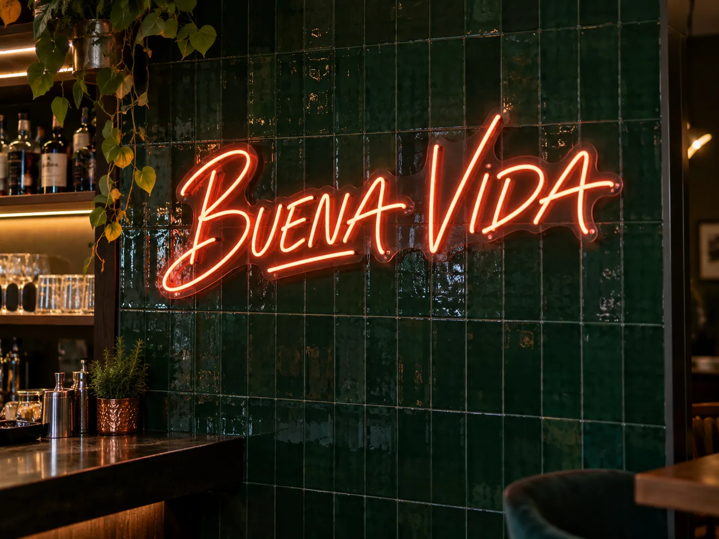 Neón personalizado BUENA VIDA instalado sobre una pared verde en un bar